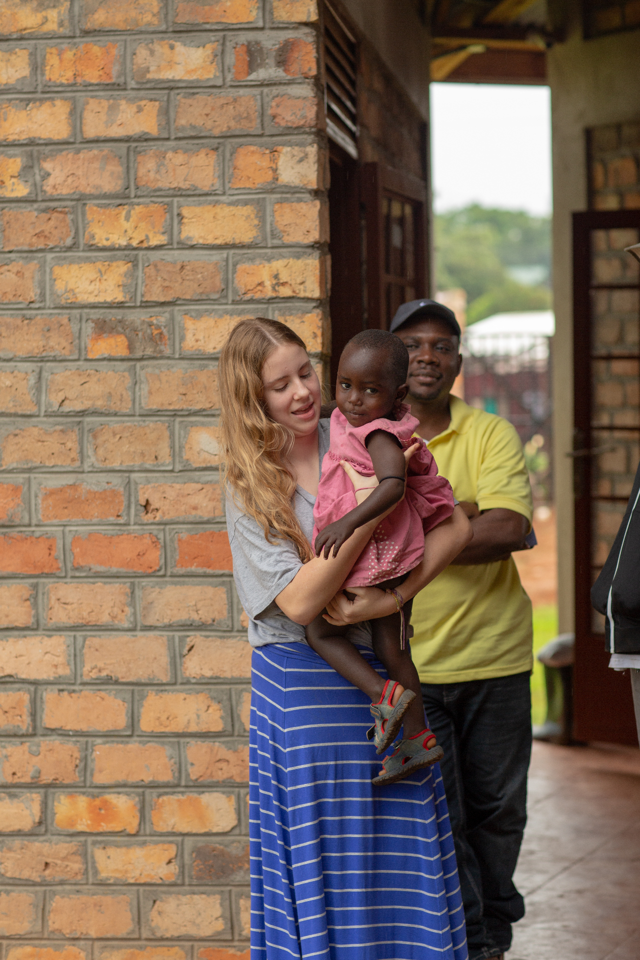 Volunteer holding a child alongside a Ugandan community member